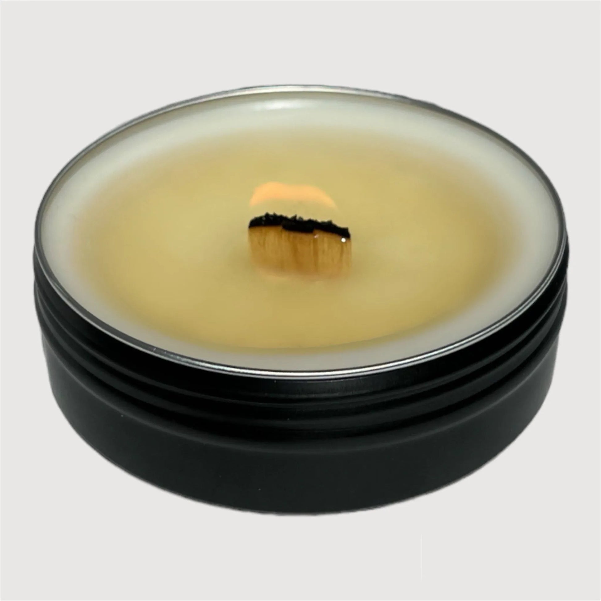 burning travel size tin candle with a wooden wick