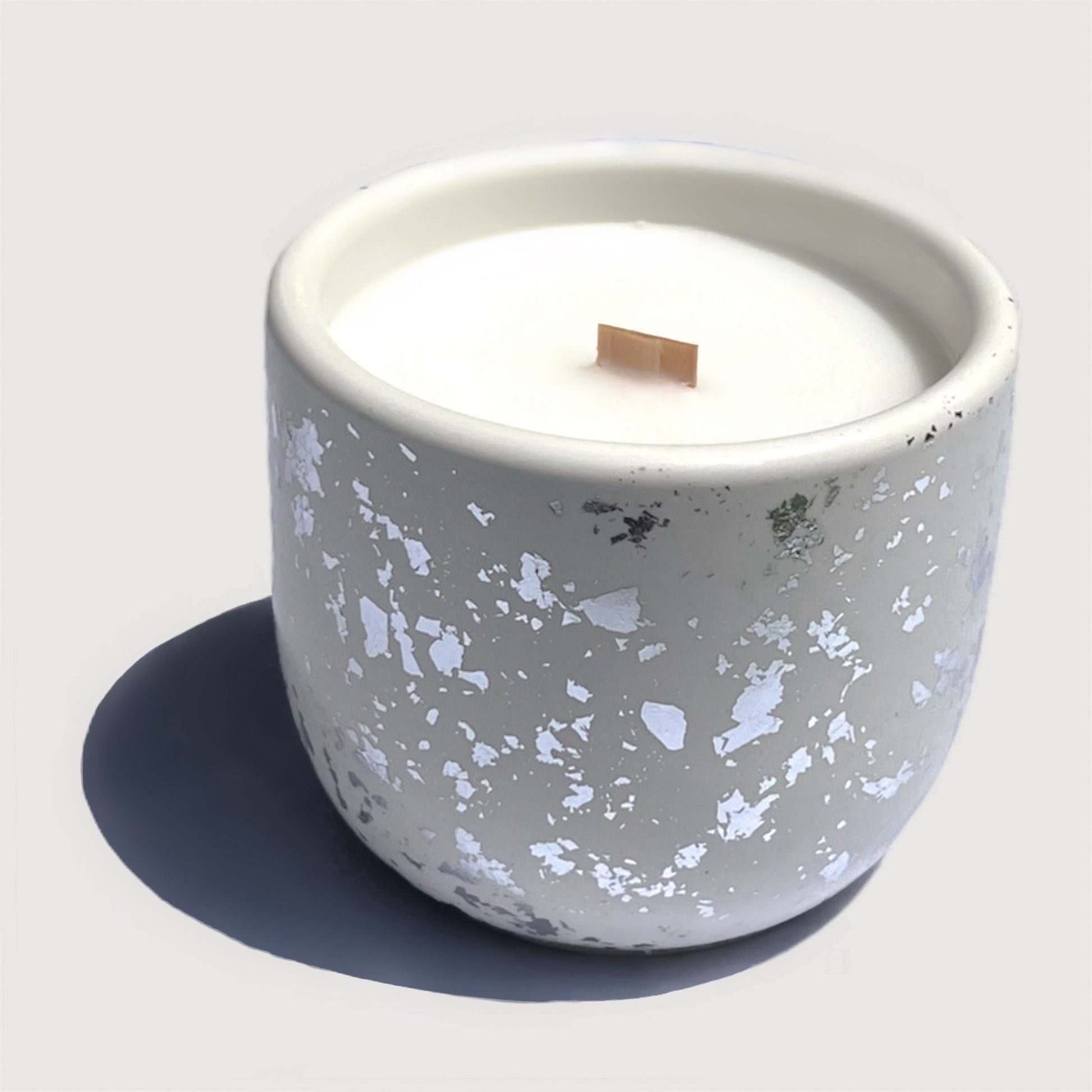 Candle in a silver white cement container on a white background