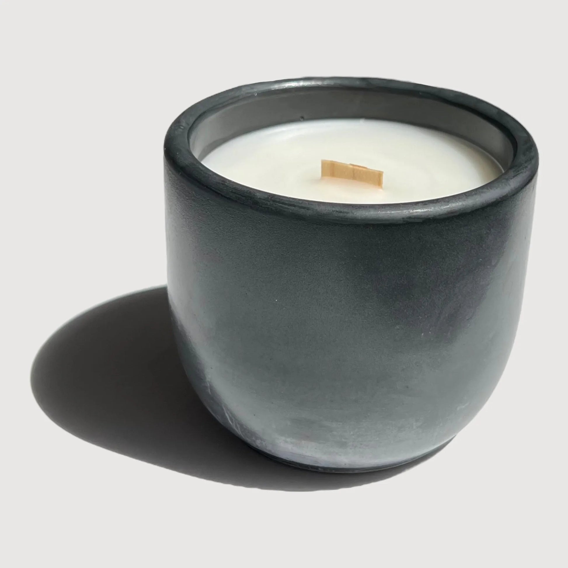 Candle in a black cement vessel with a wooden wick